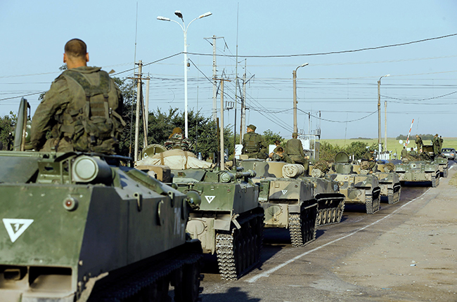 Russian military personnel sit atop armoured vehicles outside Kamensk-Shakhtinsky